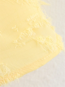 Détail du tissu jaune avec motif à vagues de franges et finition à ourlet piqué
