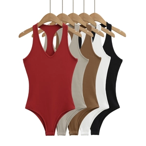 Détail de cinq bodies sans manches en maille côtelée de différentes couleurs sur un cintre