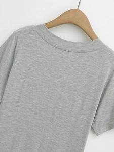 Close-up detail of grey short-sleeve knit top with textured fabric on wooden hanger