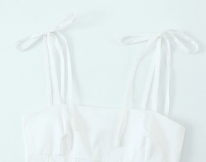 Detailansicht eines weißen Camisole-Tops mit eleganten Schleifenträgern und feiner Verarbeitung