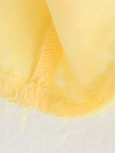 Gros plan détaillé sur le tissu en organza jaune avec bords effilochés et coutures internes