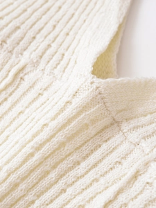 Gros plan sur l'encolure en maille crème avec côtes verticales et tissage ajouré