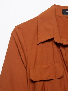 Macro detail of dark orange poplin shirt with pointed collar and double-stitched chest pocket