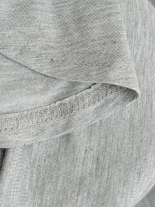 Macro shot of heather grey knitted t-shirt showing high-quality double-needle hem stitching