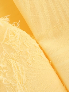 Détail du tissu texturé jaune clair avec de longues franges décoratives élégantes