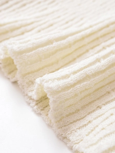 Vue macro détaillée de la texture en maille côtelée crème de cette robe longue