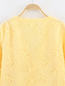 Détail d'une chemise jaune clair montrant la texture unique à franges 3D du tissu