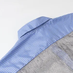 Détail du tissu en coton à rayures bleues avec des paillettes argentées sur la chemise