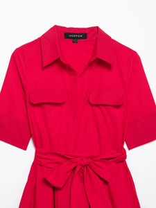 Detail of rose red poplin shirt dress featuring flap pockets and a belted waist bow