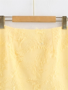 Vue détaillée du tissu jaune pâle avec une texture artistique à franges et à pompons