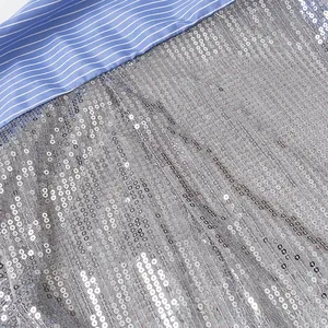 Vue macro de paillettes argentées cousues sur un tissu de chemise à rayures bleues et blanches