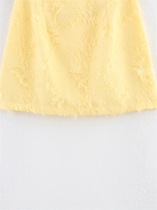 Détail d'une mini-jupe jaune pâle avec jacquard à plumes texturées et tissu à franges