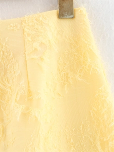 Gros plan détaillé du tissu jaune pâle avec franges 3D et texture tissée complexe