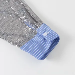 Détail de la manche à paillettes argentées avec poignet à rayures bleues et blanches