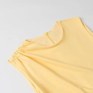 Détail d'une robe sans manches jaune clair avec épaules froncées et fermeture éclair invisible