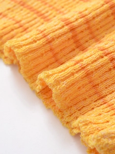 Gros plan sur un tissu en maille côtelée à rayures orange et jaunes avec texture douce