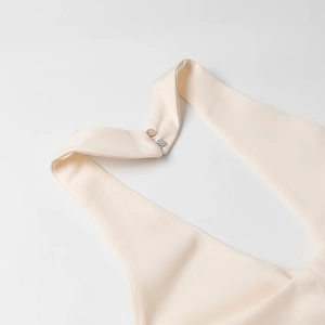 Detail of elegant off-white halter neckline with woven texture and double pearl buttons