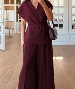 Detail view of burgundy wrap top with side tie belt and matching wide-leg trousers