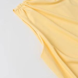Détail de l'épaule froncée et de la texture plissée d'une robe courte jaune clair
