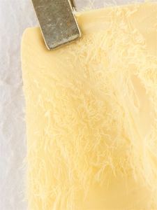 Gros plan sur un tissu jaune clair avec franges plumetées et détails de texture jacquard