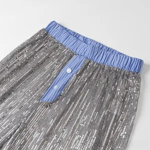 Détail du pantalon à paillettes avec taille élastique à rayures bleues et bouton blanc