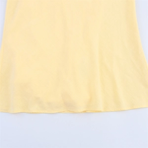 Detailed macro view of the textured linen blend fabric and hem stitching on the yellow dress