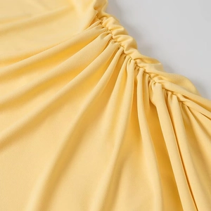 Gros plan détaillé du drapé latéral sur une robe jaune clair au tissu texturé doux