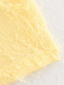 Gros plan sur un tissu jaune pâle avec des franges plumeuses et une texture de fils cils