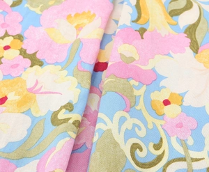 Gros plan sur un tissu floral bleu clair avec des fleurs roses et jaunes et texture fine