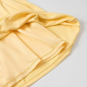 Vue détaillée de l'ourlet à double couche et des coutures sur une robe courte jaune