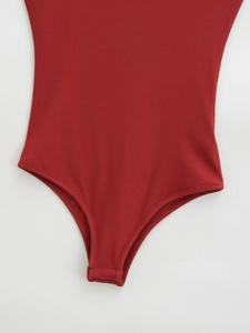 Détail d'un body rouge côtelé montrant la jambe haute et la fermeture à boutons-pression