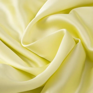Detailed view of pale yellow satin fabric with high gloss and smooth texture