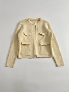 Dettaglio di un cardigan in maglia crema con quattro tasche e design testurizzato a girocollo