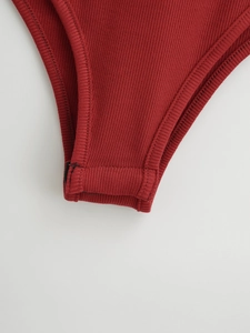 Détail du tissu côtelé et de la fermeture par boutons-pression sur le body bordeaux