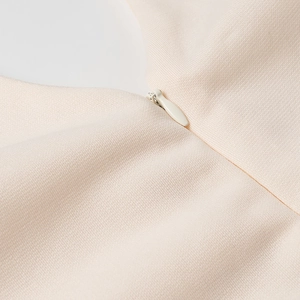 Detail shot of invisible zipper on light beige woven fabric with sleek teardrop puller