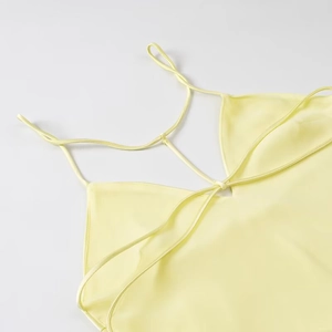 Detail of cross-strap back and smooth satin fabric texture on light yellow midi dress