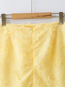 Détail de la jupe courte jaune avec texture effilochée et fermeture éclair invisible