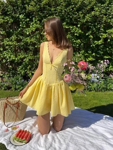 Détail d'une robe courte jaune avec tissu texturé et décolleté en V à bordures festonnées