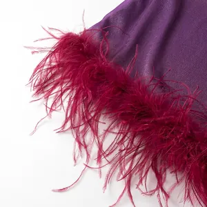 Gros plan sur le tissu tricoté violet et les plumes rouge foncé au bord de la robe