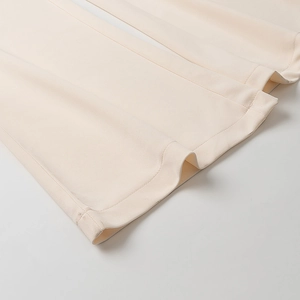 Detail view of double-stitched hem and cream cotton fabric texture on elegant jumpsuit