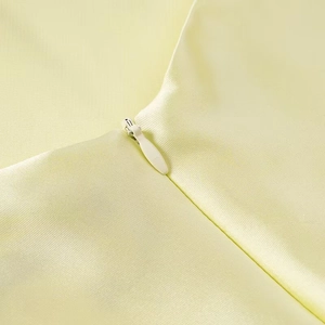 Close-up of invisible zipper detail on cream yellow midi dress with smooth fabric texture