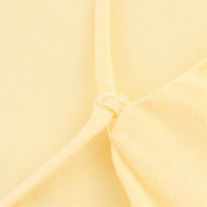 Detailed macro view of pale yellow ramie blend fabric with delicate tie-knot straps