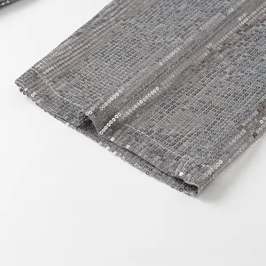 Détail macro de paillettes argentées cousues sur tissu gris pour une finition chic