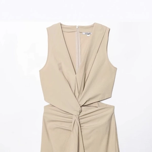 Sleeveless khaki dress with deep V-neck, waist cutout, and elegant front knot detail