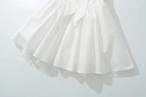 Détail de robe blanche en coton avec ourlet en dentelle et nœud décoratif élégant