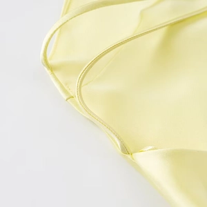 Detail of slim straps and fine stitching on a pale yellow satin midi dress