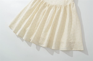 Détail d'une robe crème avec broderie anglaise florale et plis au design élégant