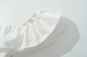 Détail de la manche d'une robe blanche avec dentelle délicate et volants élastiques fins