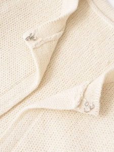 Dettaglio della chiusura a gancio in metallo sul cardigan beige in maglia grossa rifinita