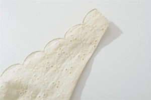 Détail de la broderie anglaise de couleur crème avec une bordure festonnée